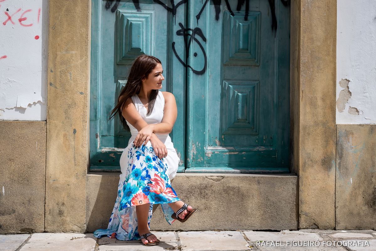 menina sentada moldura porta rustica vestido branco barra florida pernas cruzadas 
