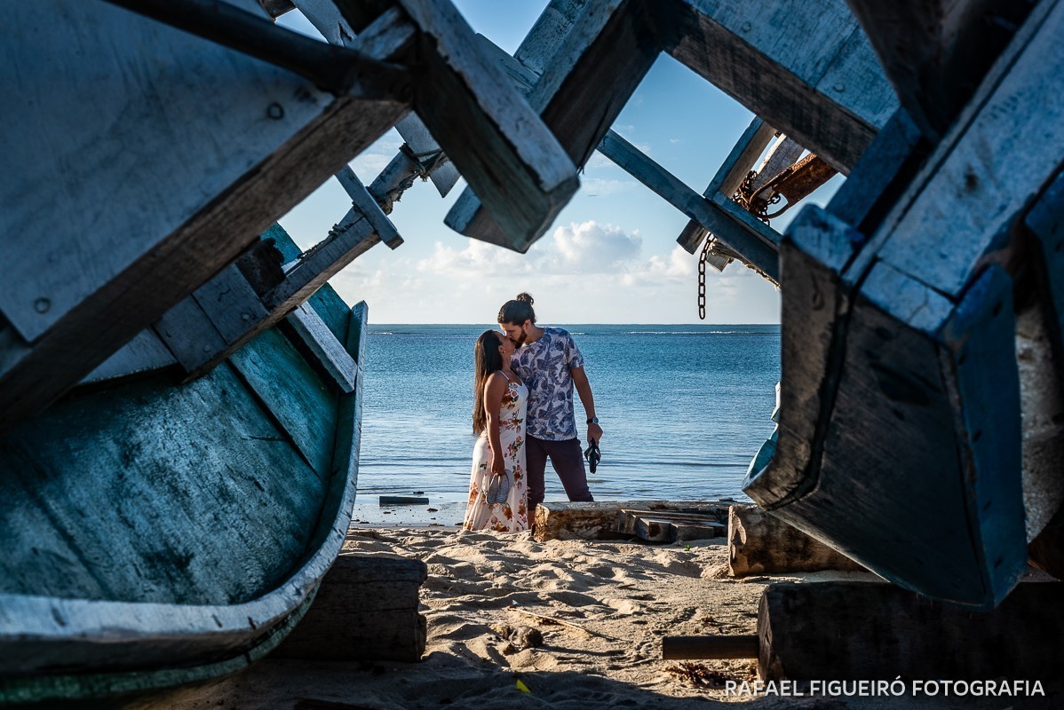 Ensaio Pre-Wedding do simpático casal Duda e Lucas, realizado na Praia de Tamandaré-PE Sul de Pernambuco, pelas redondezas da Igreja de São Perdo. casal beijando jangadas perspectiva camadas azul lindo