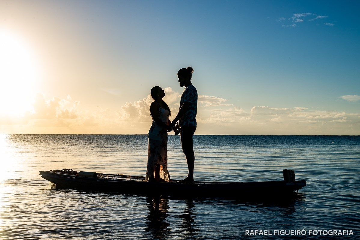 Ensaio Pre-Wedding do simpático casal Duda e Lucas, realizado na Praia de Tamandaré-PE Sul de Pernambuco, pelas redondezas da Igreja de São Perdo. casal maos dadas jangada contra sol luz