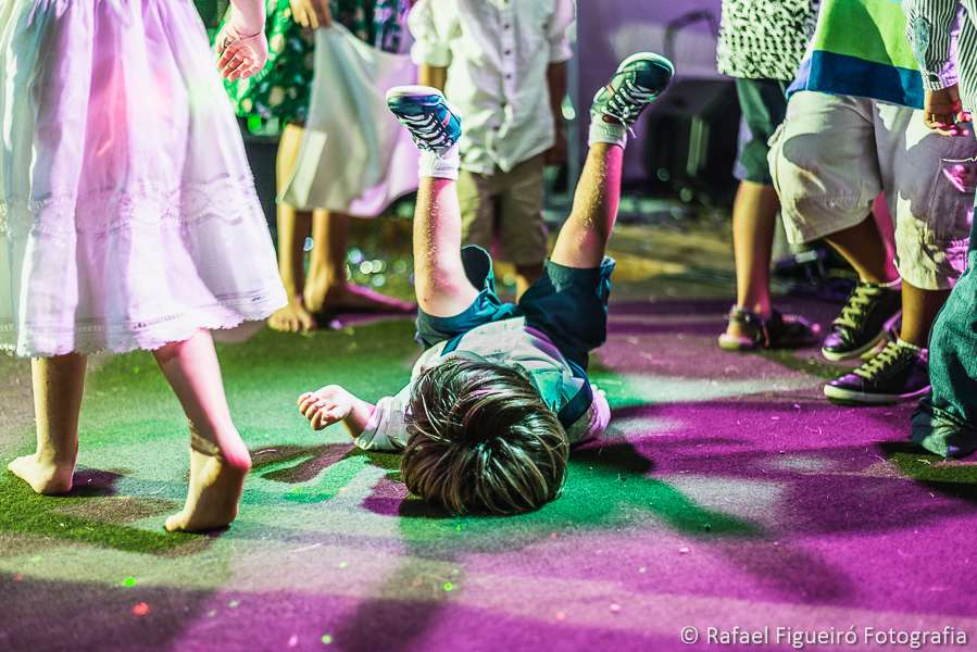 menino caido na pista de dança com pernas para o alto em momento de pura alegria de criança na praia do serrambí resort  fotografado por Rafael Figueiró fotógrafo de casamentos em Recife-PE pernambuco