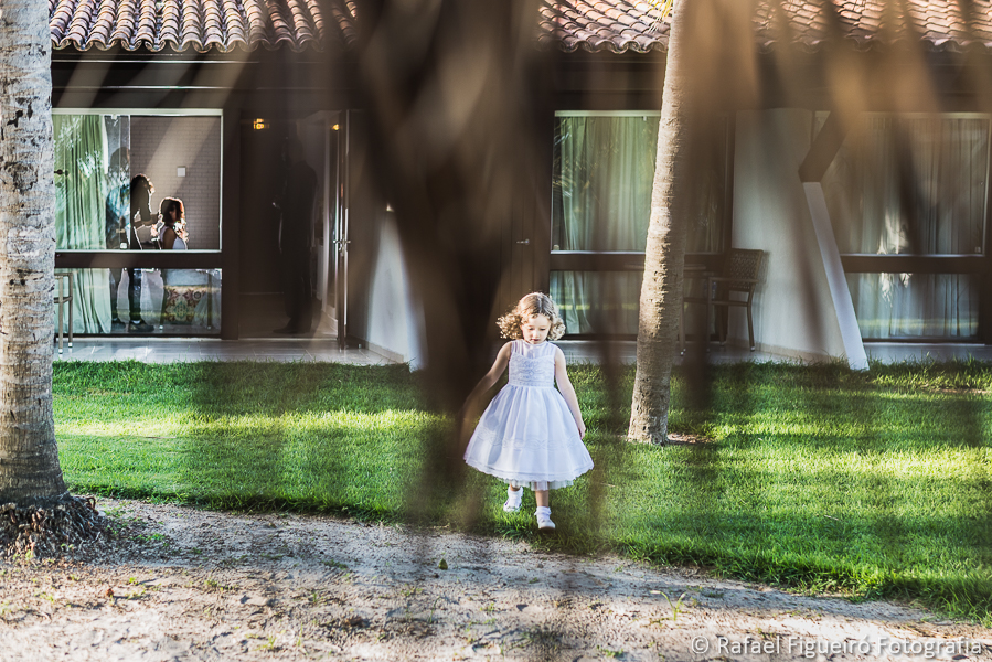 daminha de honra da noiva brincando no jardim enquanto a noiva é maquiada ao fundo com iluminação diferenciada fotografado por Rafael Figueiró fotógrafo de casamentos em Recife-PE pernambuco