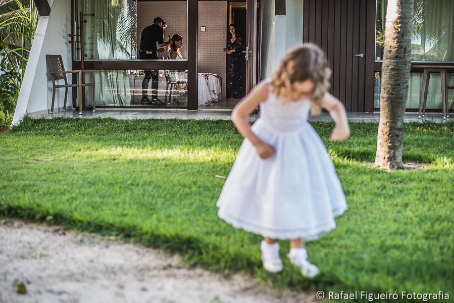 daminha de honra da noiva brincando no jardim enquanto a noiva é maquiada ao fundo com iluminação diferenciada fotografado por Rafael Figueiró fotógrafo de casamentos em Recife-PE pernambuco