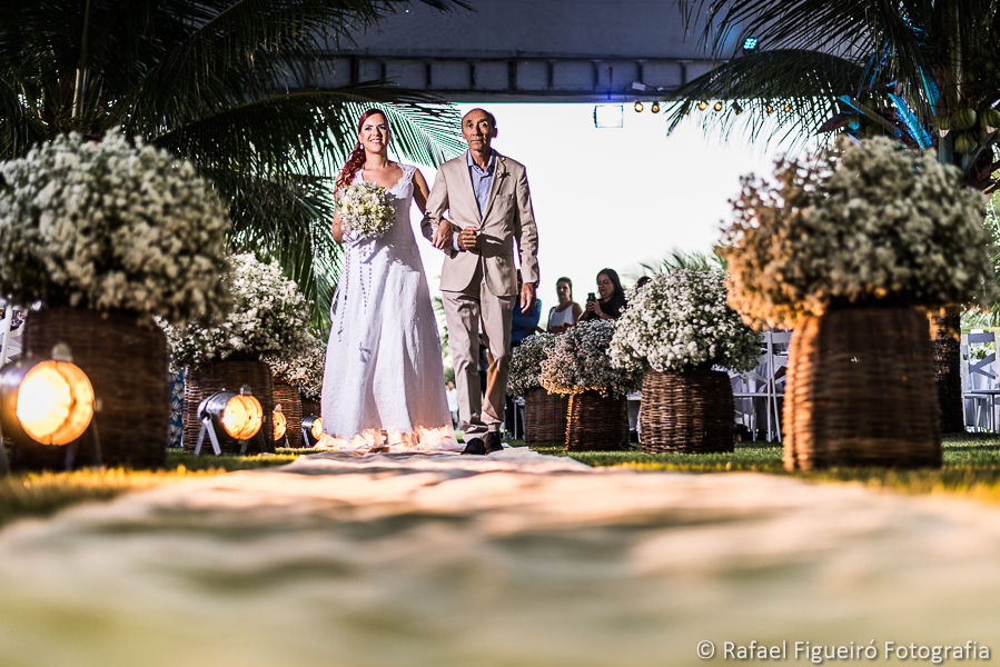Entrada da noiva com o pai casamento na praia em meio aos coqueiros em serrambi resort com iluminação no chão fotografado por Rafael Figueiró fotógrafo de casamentos em Recife-PE pernambuco