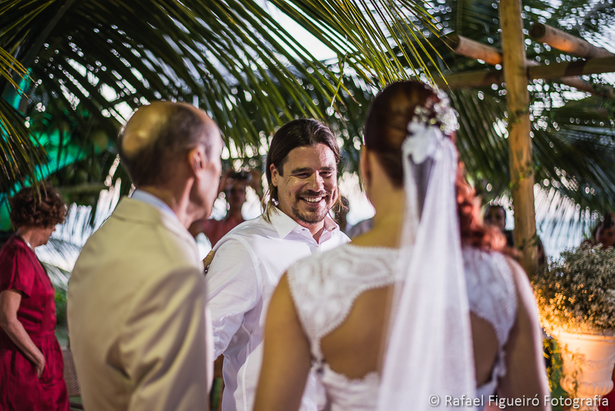 Troca de olhares entre o noivo e a noiva quando se encontram no altar em meio a coqueiros na praia de serrambi resort fotografado por Rafael Figueiró fotógrafo de casamentos em Recife-PE pernambuco