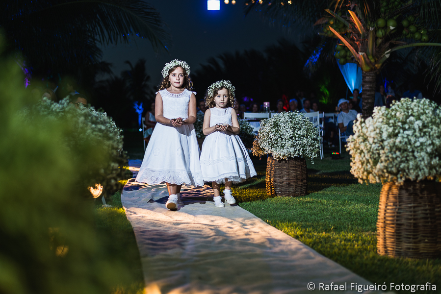 Daminhas de honra entrando com as alianças no casamento na praia do Serrambí Resort em meio aos coqueiros fotografado por Rafael Figueiró fotógrafo de casamentos em Recife-PE pernambuco