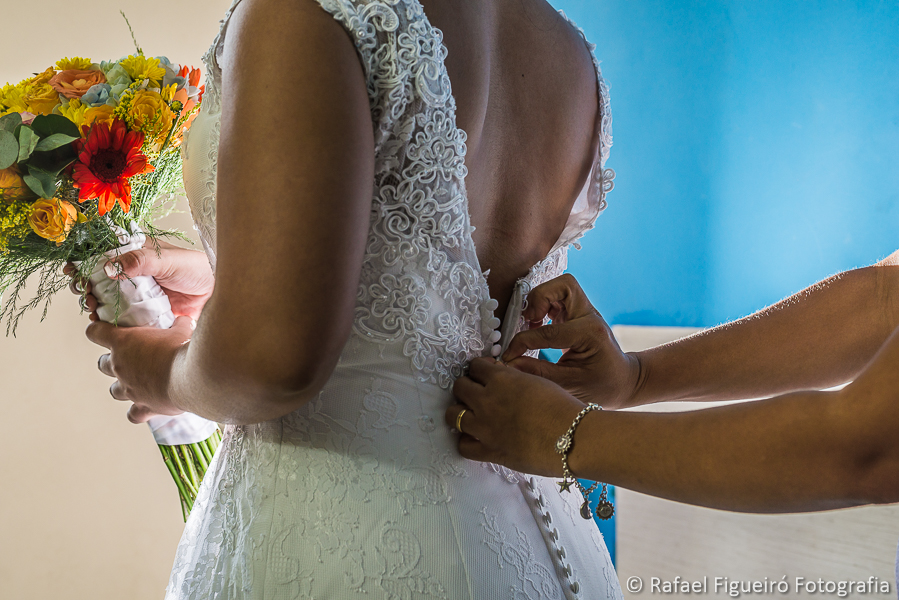 Mãos abotoam a fila de botões do vestido da noiva fotografado por Rafael Figueiró melhor fotógrafo de casamentos de Recife-PE