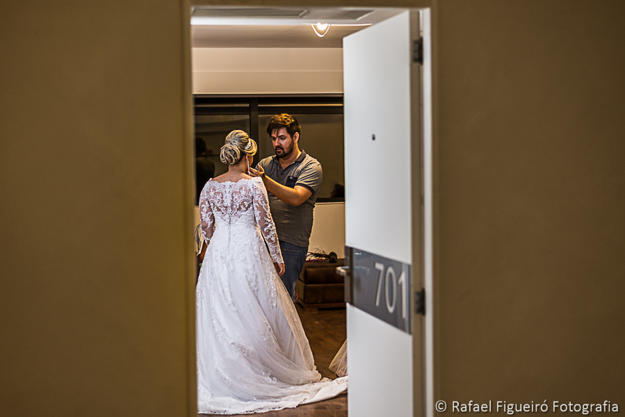 maquiador finalizando detalhes da noiva visto pela porta entre aberta fotografado por Rafael Figueiró melhor fotógrafo de casamentos em recife-pe