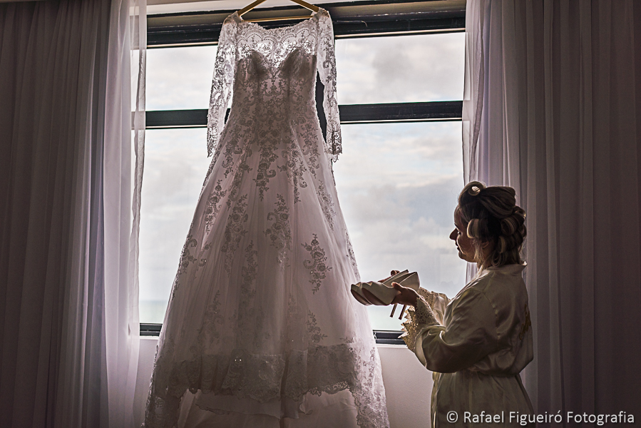 Noiva admira seu vestido e segura sapatos nas mãos fotografado por rafael figueiró melhor fotógrafo de casamentos em recife