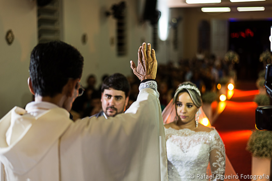 Padre abençoa os noivos com convidados ao fundo fotografado por Rafael Figueiró fotógrafo melhor de casamentos em Recife-PE
