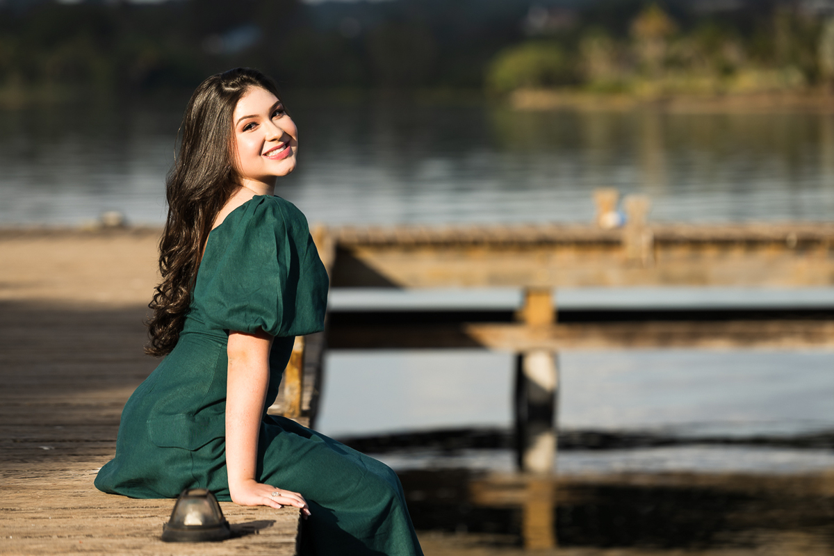 Foto Debutante sentada sob o deck de madeira do Lago Sul em Brasília. 