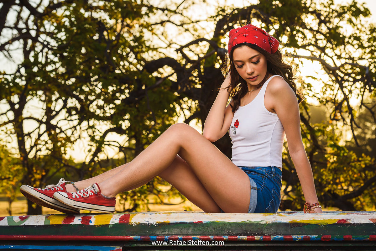 Foto do ensaio de 15 anos da Bruna sentada sobre a Kombi estacionada na L4 Norte em Brasília em frente a Universidade de Brasília.