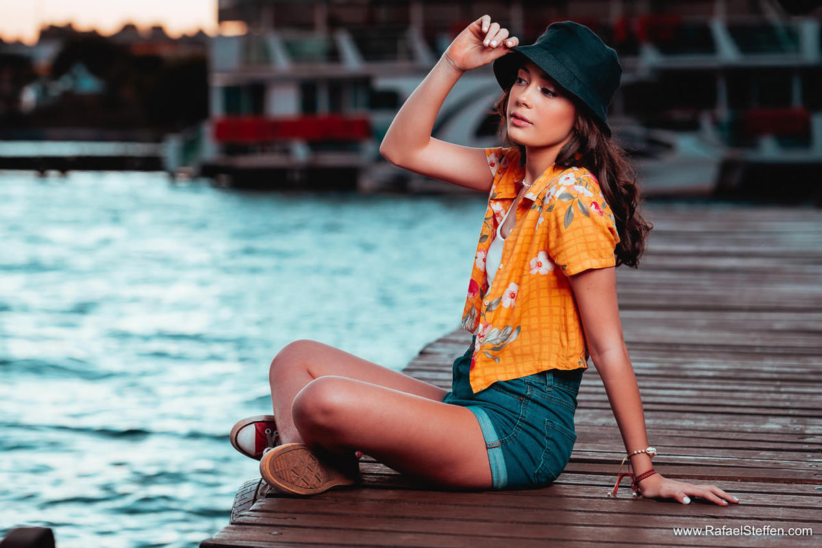 Ensaio de 15 anos da Bruna sentada no deck de madeira do restaurante Coco Bambu do Lago Sul