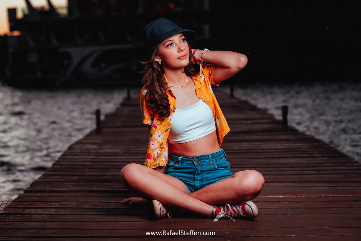 Ensaio de 15 anos da Bruna sentada no deck de madeira do restaurante Coco Bambu do Lago Sul