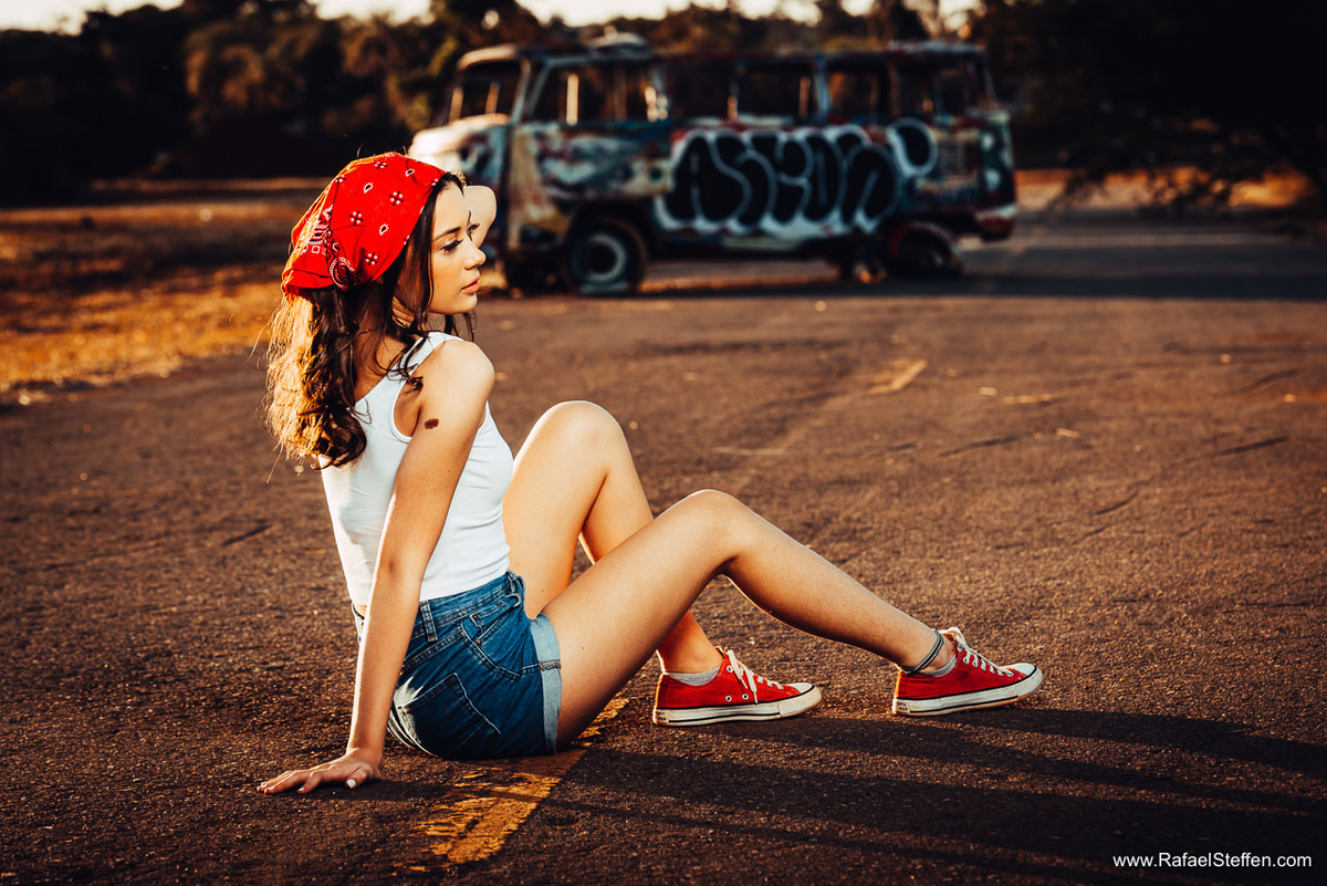 Ensaio de 15 anos da Bruna Rangel sentada na pista no pôr do sol com a Kombi no fundo na L4 Norte em Brasília em frente a Universidade de Brasília.