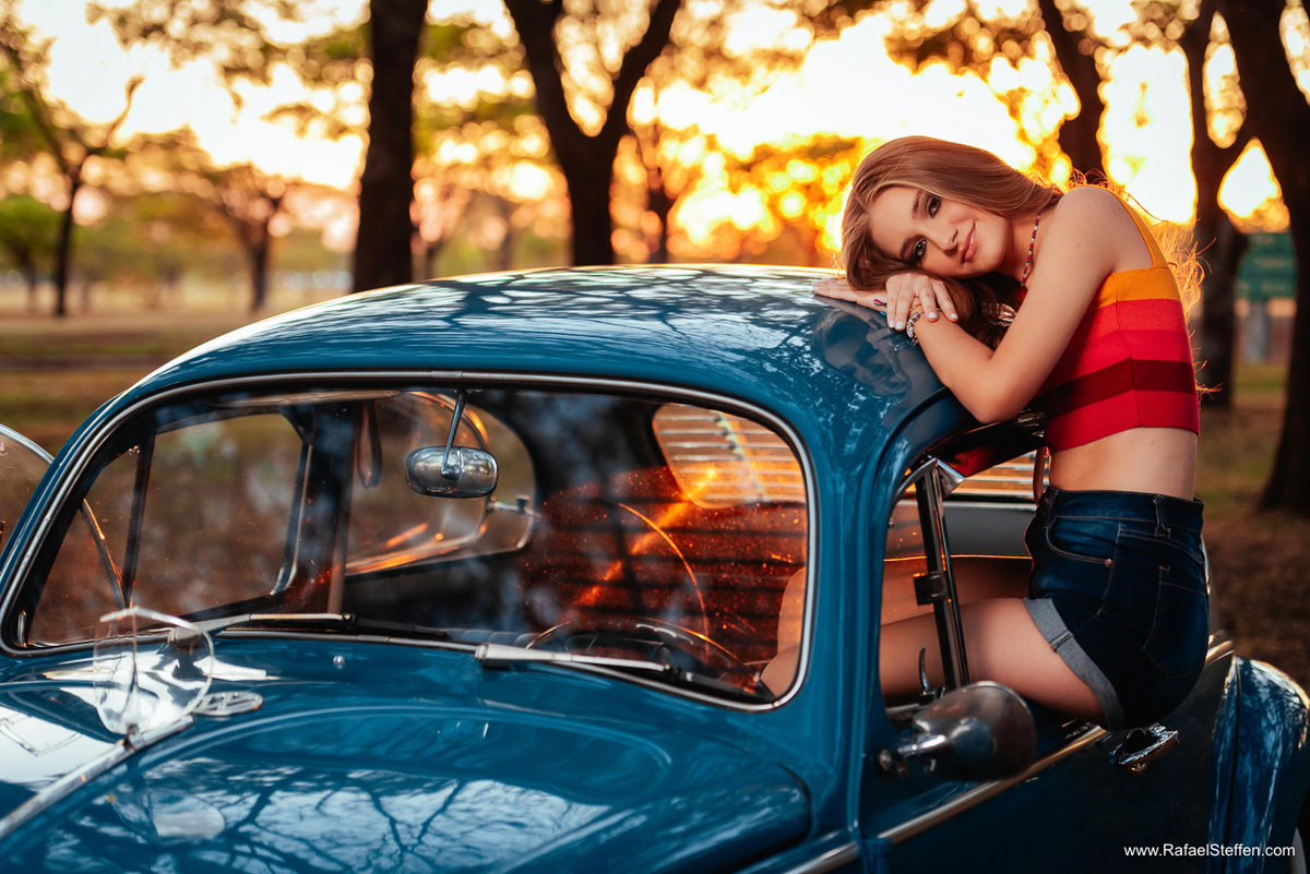 Ensaio de quinze anos da Ester sentada na Janela do Fusca azul durante o pôr do Sol em Brasília fotografada por Rafael Steffen Fotografia.