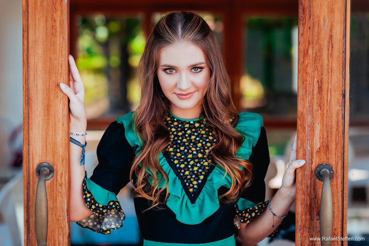 Ensaio de quinze anos da Ester fotografada na janela olhando para fora.