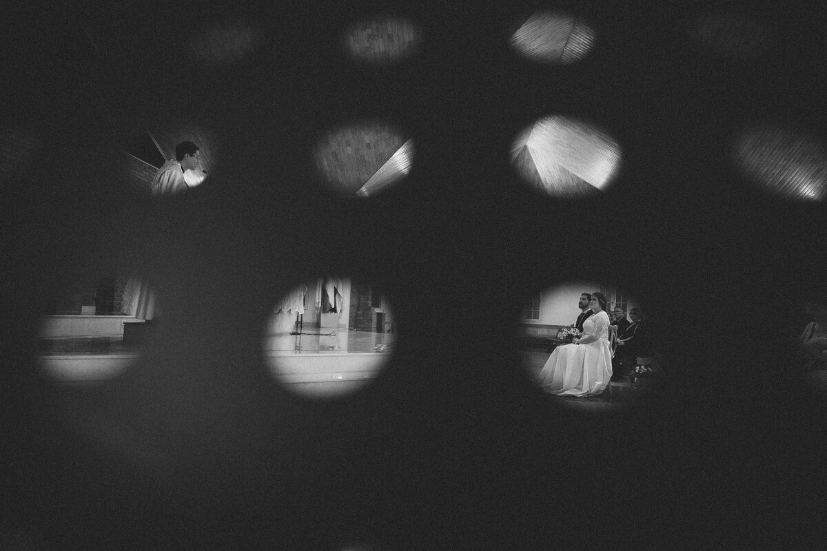 momento de lectura de la palabra donde el cura párroco y los novios son observado por entre los agujeros del apoya libros usado por los músicos