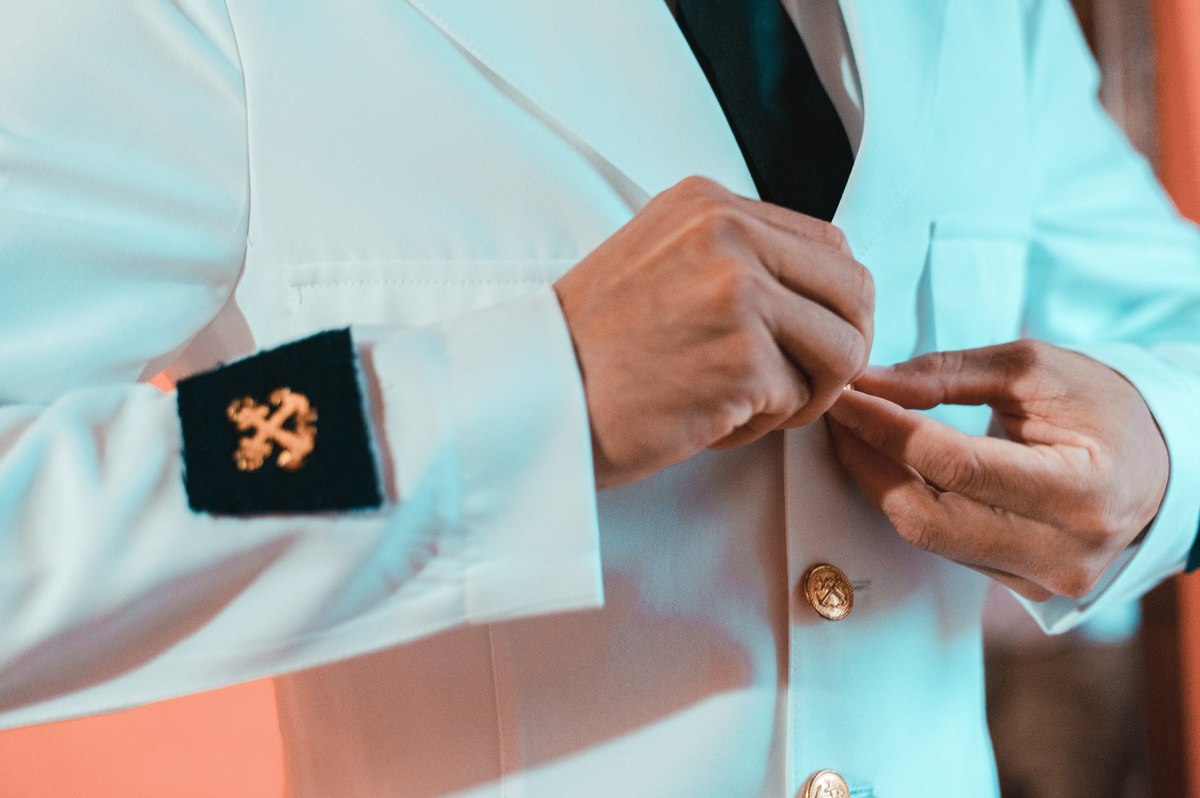 novio abrochándose el traje blanco militar para la boda