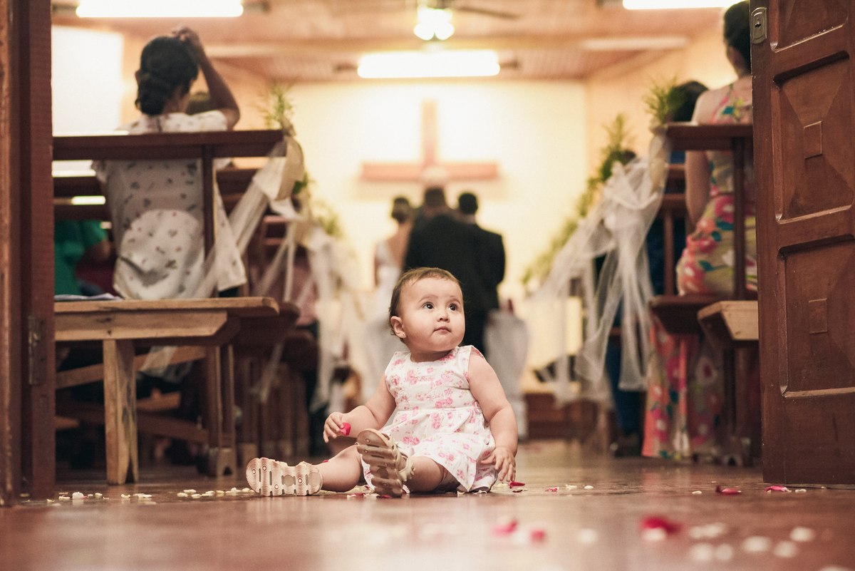 niña juega tirada en el suelo mientras ocurre la ceremonia religiosa