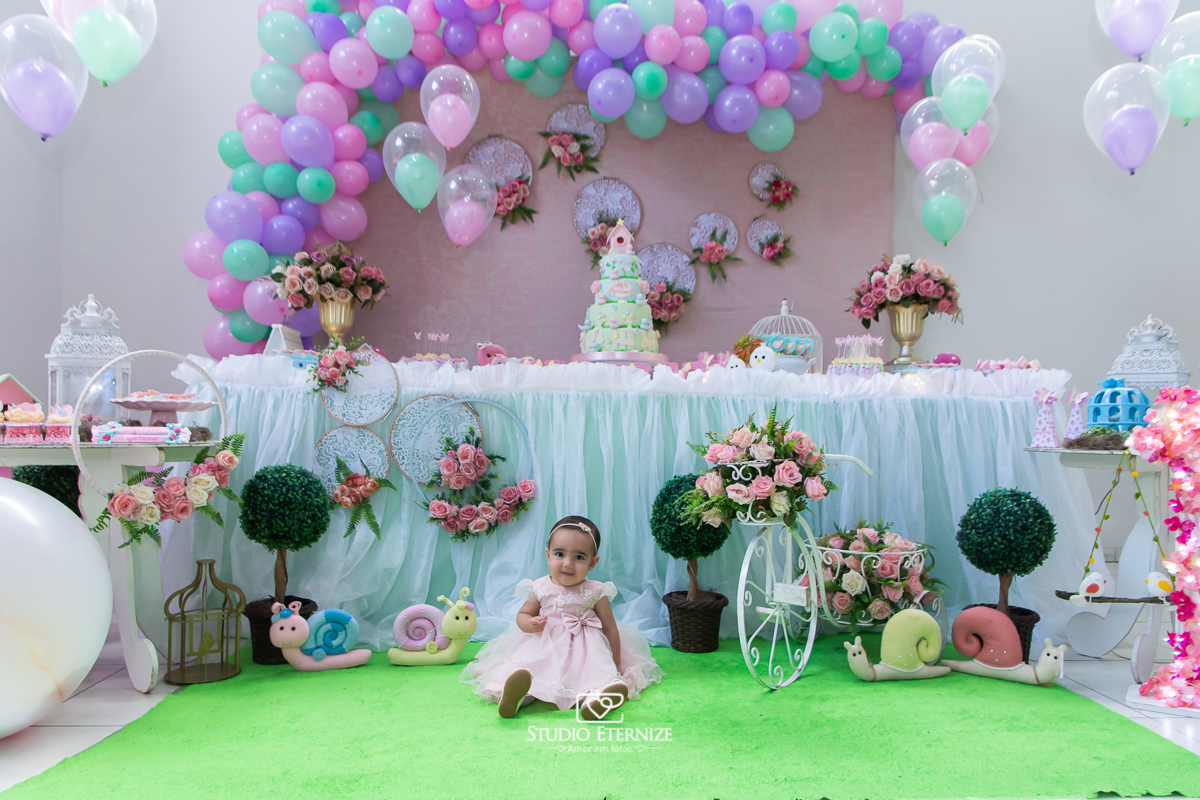 Fotografia da aniversariante Giovanna em frente sua mesa de bolo.