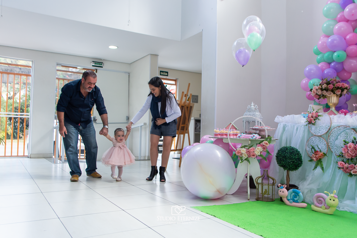 Fotografia da aniversariante Giovanna chegando com seus pais na sua festa.