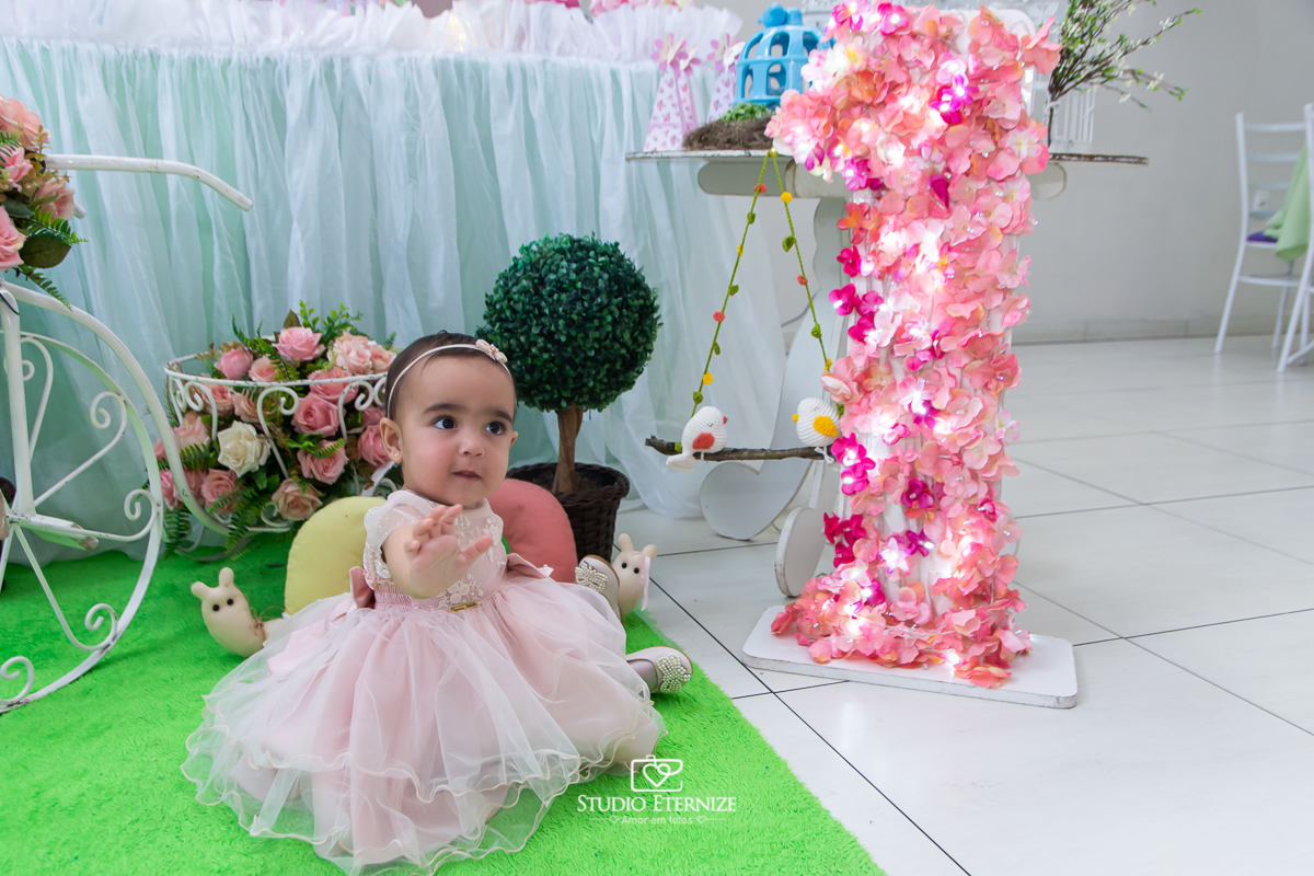 Fotografia da aniversariante Giovanna em frente sua mesa de bolo.