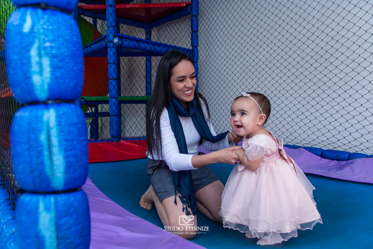 Fotografia da aniversariante brincando no pula-pula com sua mãe.