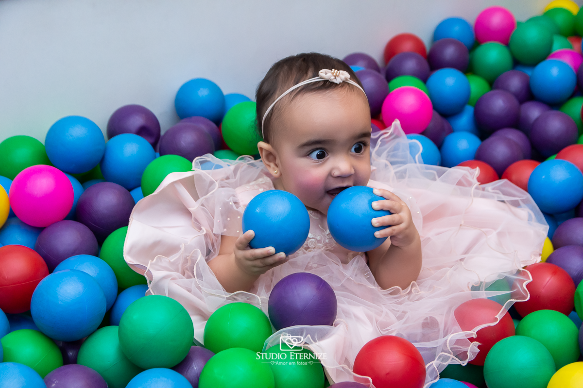 Fotografia da aniversariante brincando na piscina de bolinha.