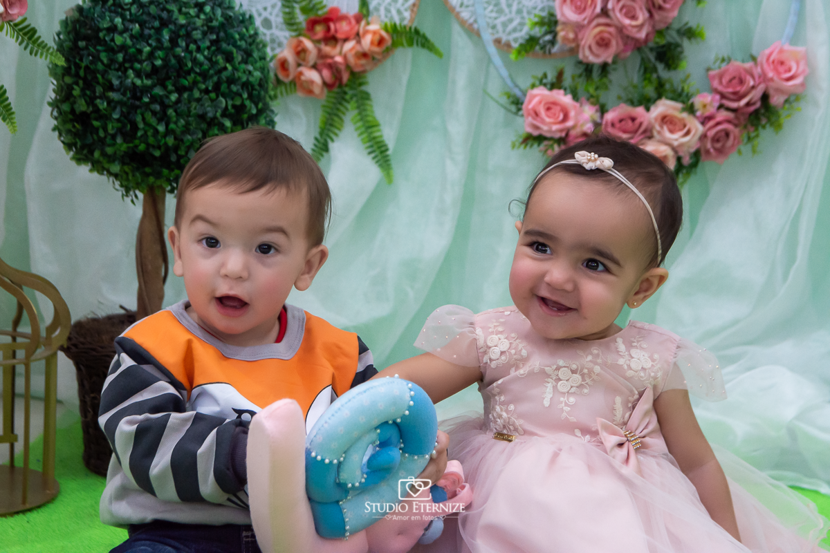 Fotografia da aniversariante com seu amiguinho na mesa do bolo.