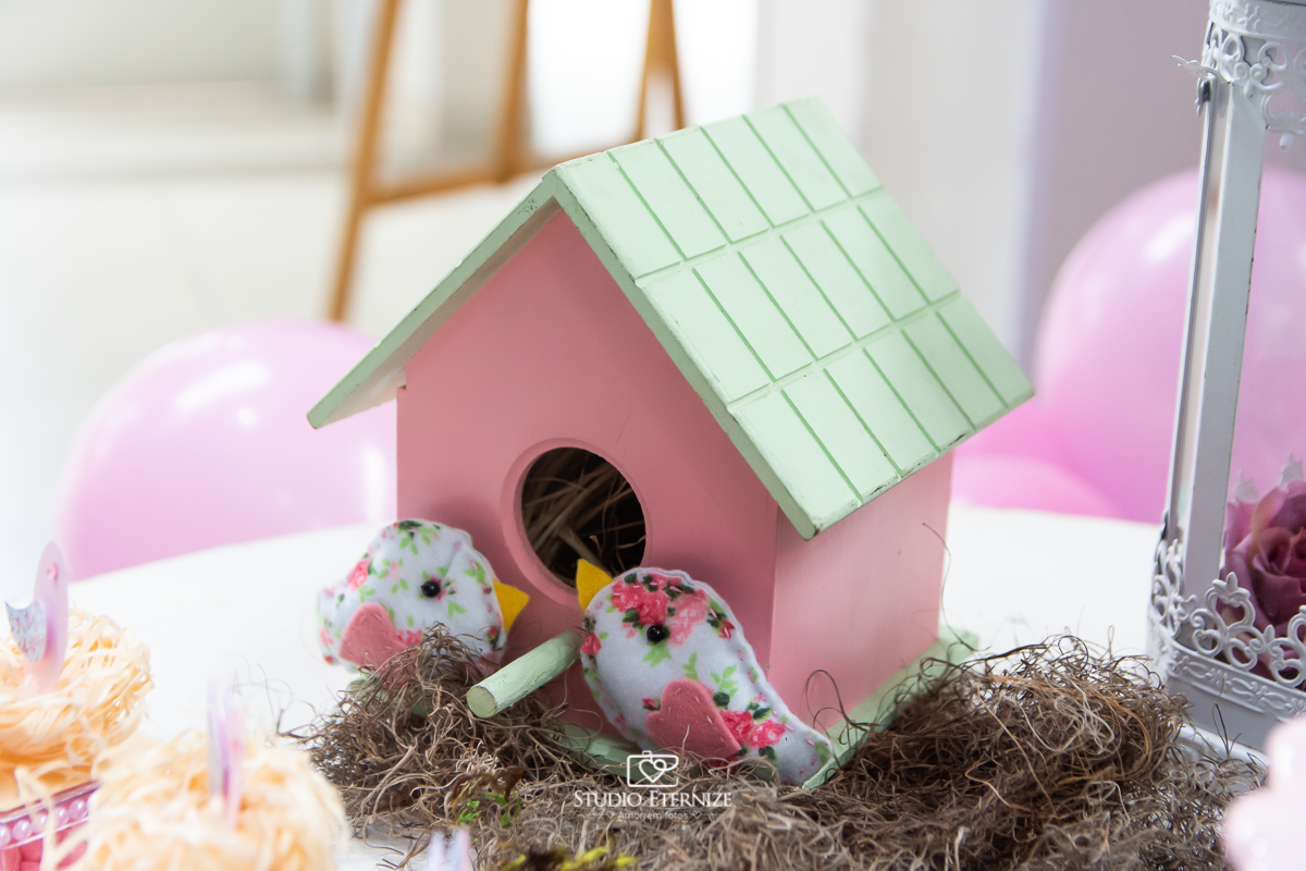 Fotografia do aniversário de 1 ano da Giovanna realizado no Buffet Fábrica da Diversão. Detalhe da decoração da mesa com uma casinha de passarinho.