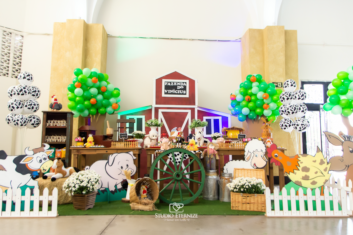 Fotografia de aniversario infantil no tema fazendinha realizado em Poços de Caldas. Decoração da mesa do bolo com vários elementos da fazendinha. 