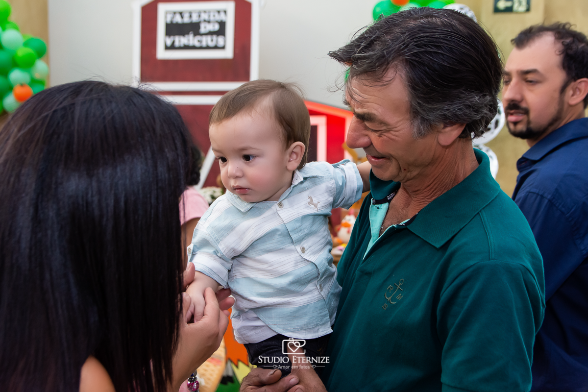 Fotografia de aniversario infantil no tema fazendinha realizado em Poços de Caldas. Aniversariante no colo do avó cumprimentando os convidados.