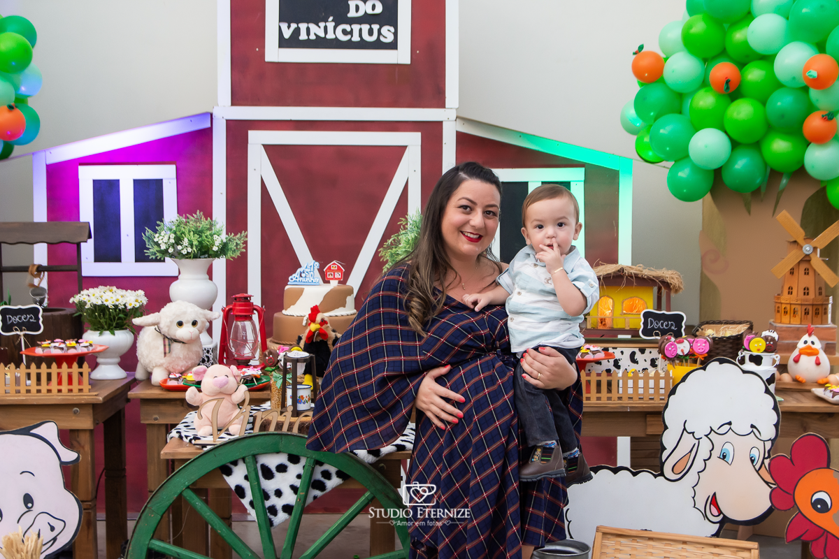 Fotografia de aniversario infantil no tema fazendinha realizado em Poços de Caldas. Mãe e aniversariante posando para uma foto na frente da mesa do bolo.
