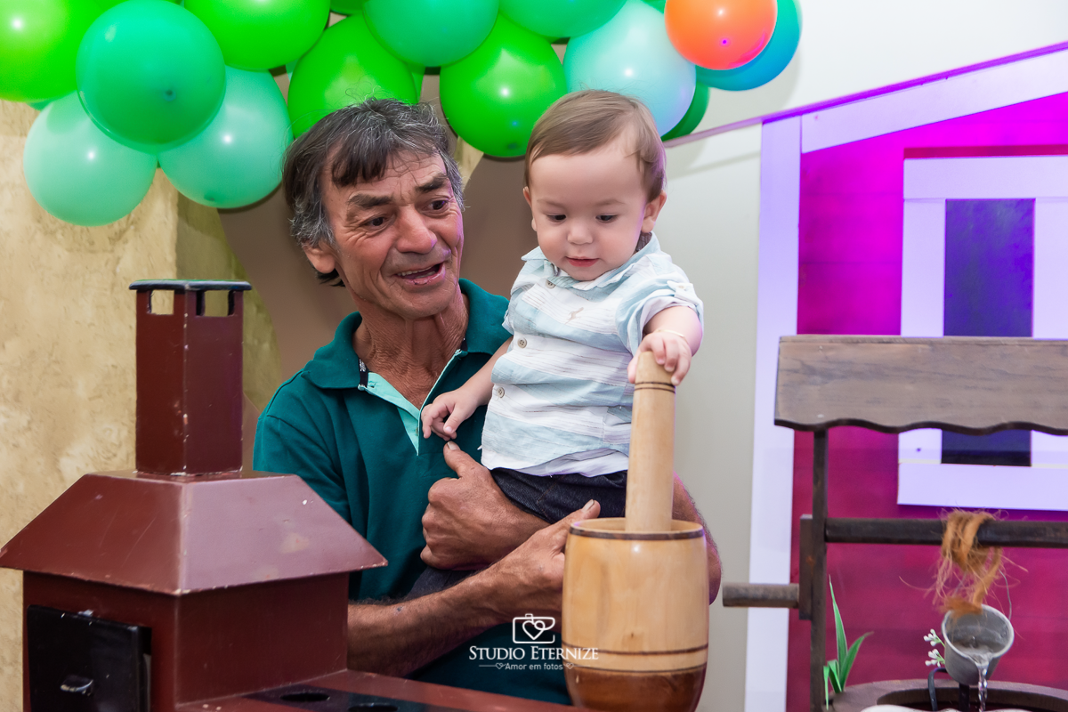 Fotografia de aniversario infantil no tema fazendinha realizado em Poços de Caldas. Aniversariante no colo do avô brincando.