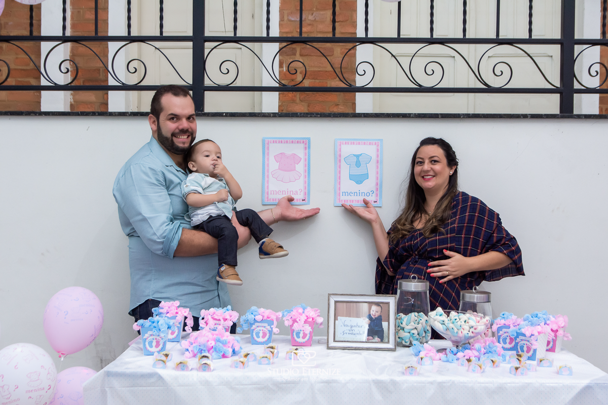 Fotografia de aniversario infantil no tema fazendinha realizado em Poços de 
 Caldas. Pais e aniversariante posando para uma foto na frente da mesa da descoberta do sexo do próximo bebê.