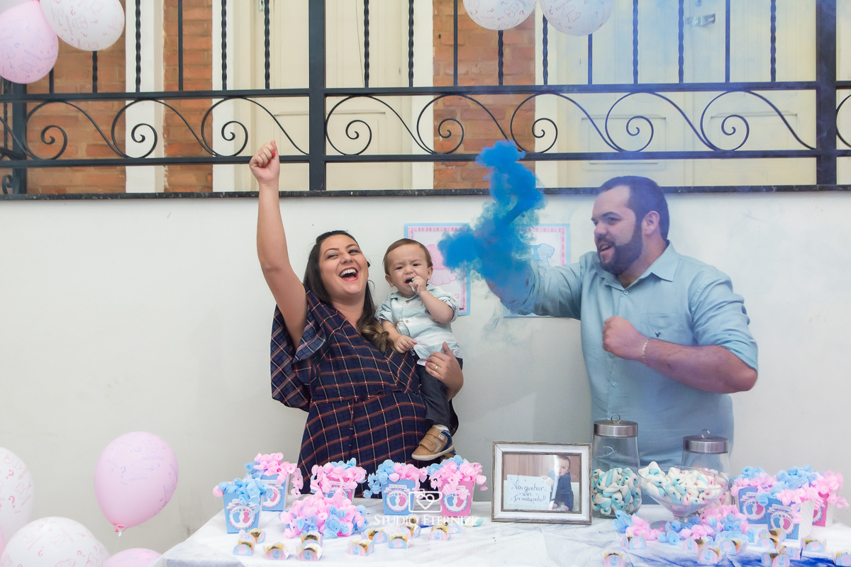 Fotografia de aniversario infantil no tema fazendinha realizado em Poços de Caldas. Pais e aniversariante na mesa da descobrem que o próximo bebê é um menino.