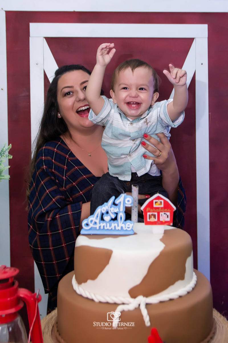 Fotografia de aniversario infantil no tema fazendinha realizado em Poços de Caldas. Mãe e aniversariante na mesa do bolo se divertindo.