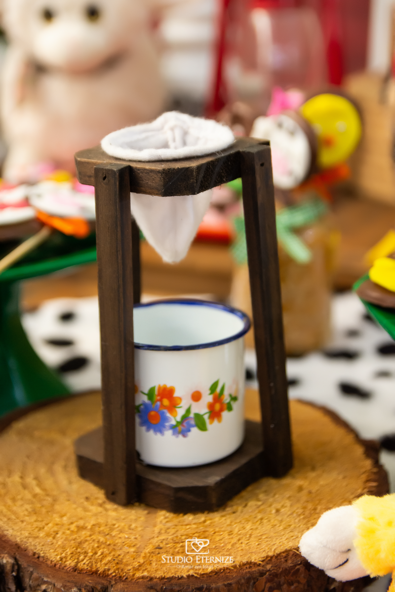 Fotografia de aniversario infantil no tema fazendinha. Detalhe da decoração da mesa do bolo com um mini coador e uma canequinha para café.