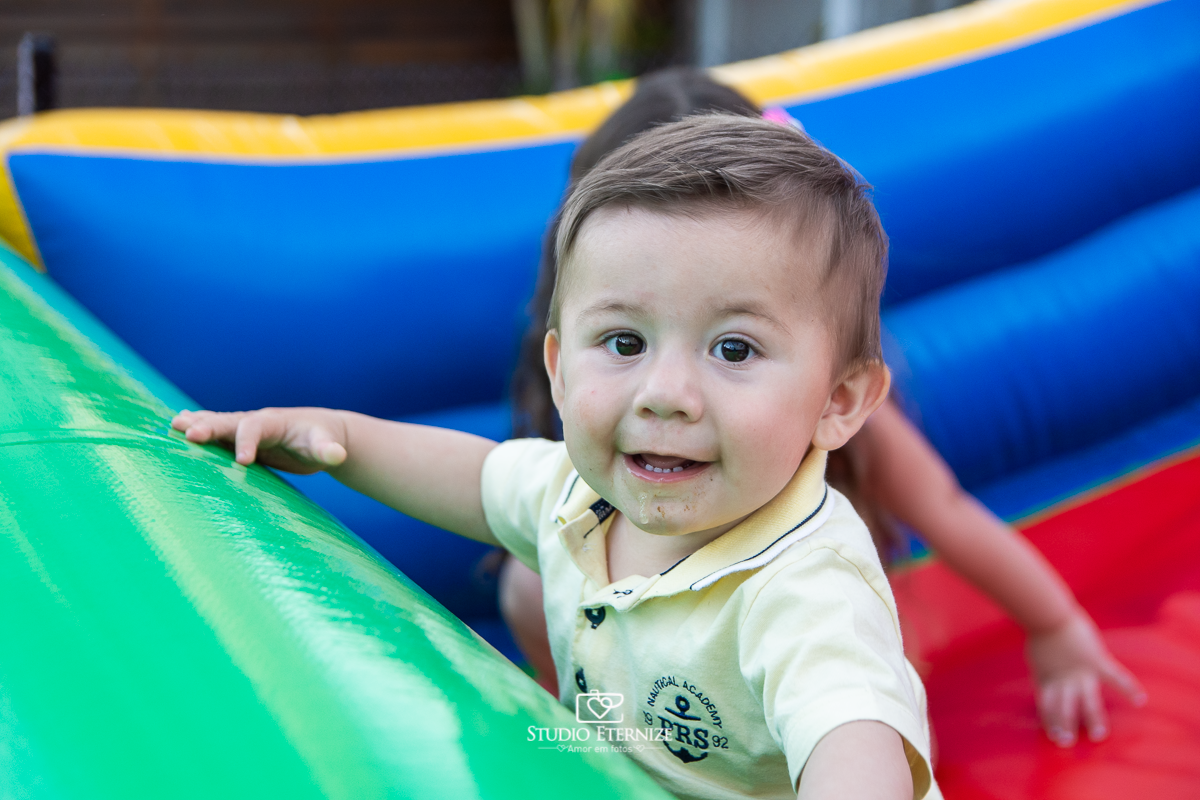 Fotografia de aniversário infantil realizado pelo Studio Eternize em Poços de Caldas. Tema da festa cientista. Close do aniversariante no brinquedo de escorregar. 