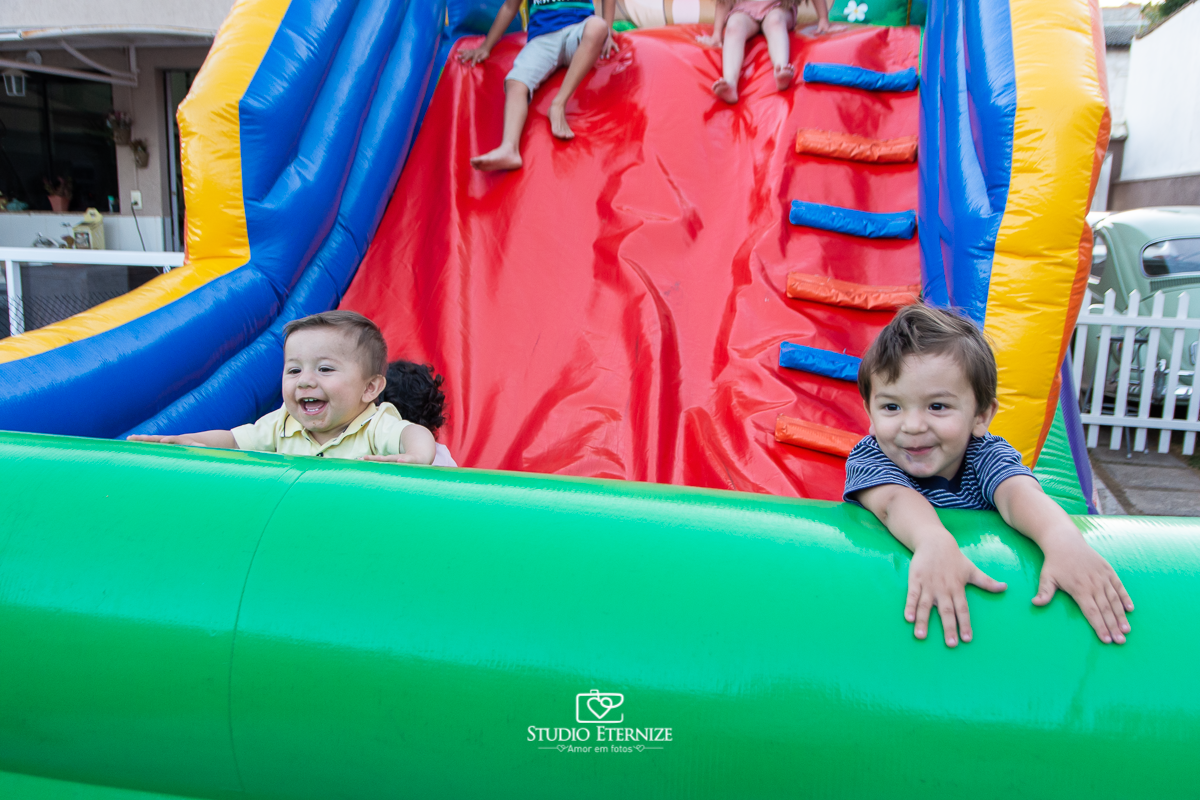 Fotografia de aniversário infantil realizado pelo Studio Eternize em Poços de Caldas. Tema da festa cientista. Aniversariante e seu irmão no brinquedo de escorregar.
