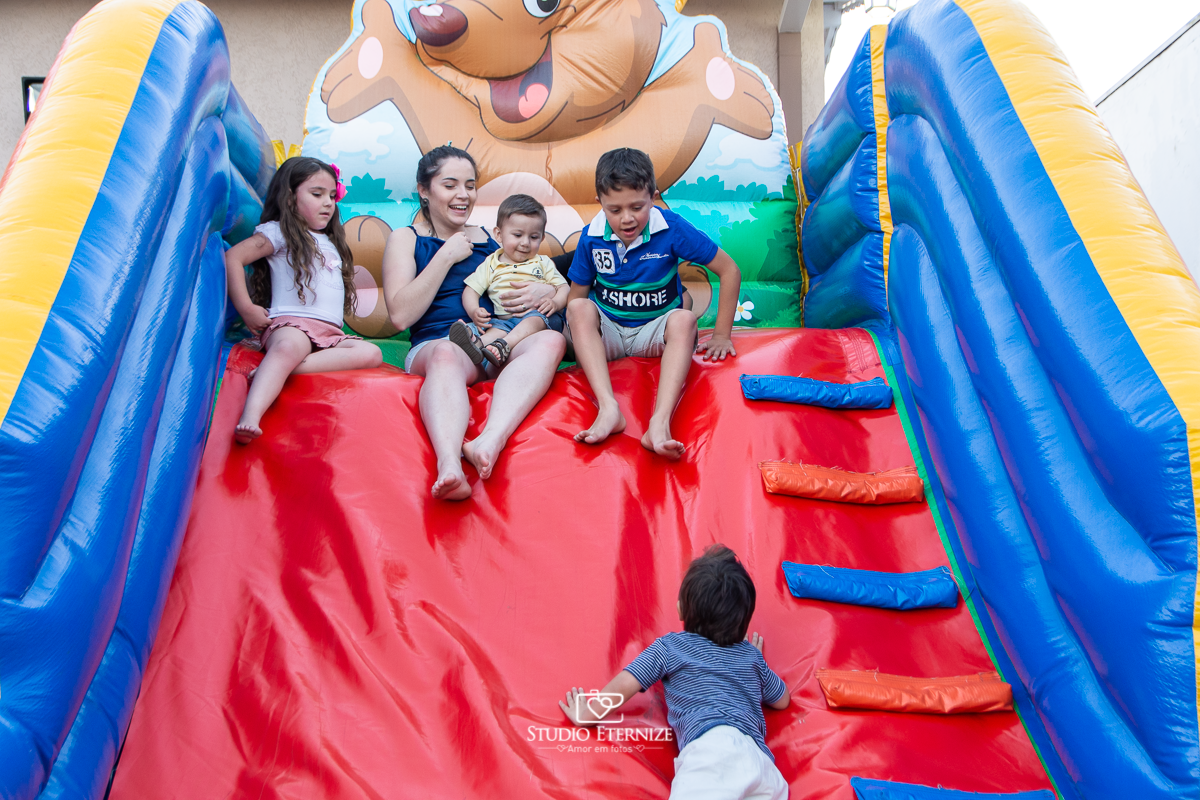 Fotografia de aniversário infantil realizado pelo Studio Eternize em Poços de Caldas. Tema da festa cientista. Aniversariante e seus primos em cima do escorrega esperando seu irmão subir.