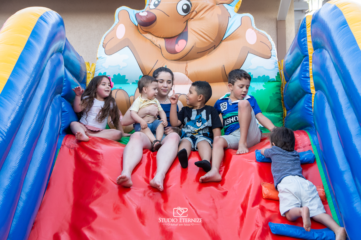 Fotografia de aniversário infantil realizado pelo Studio Eternize em Poços de Caldas. Tema da festa cientista. Aniversariante e seus primos no escorrega de ar esperando seu irmão subir.