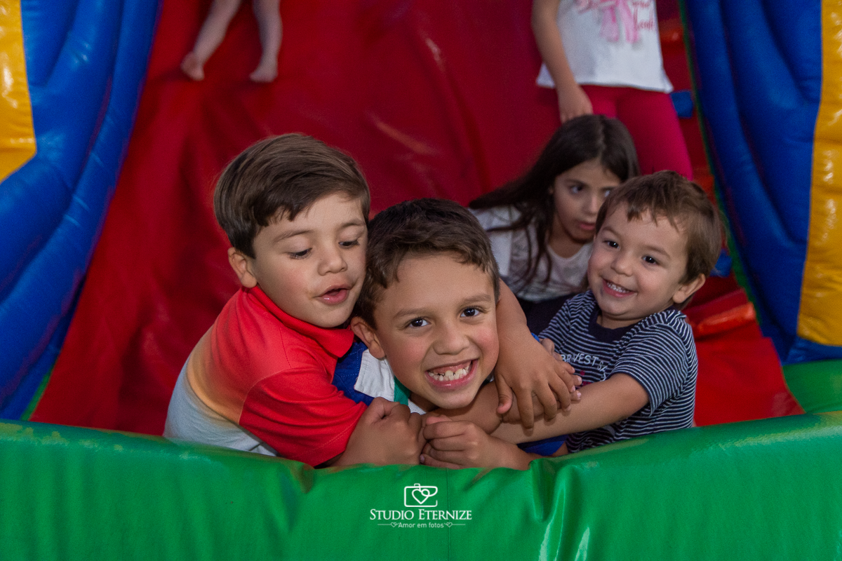 Fotografia de aniversário infantil realizado pelo Studio Eternize em Poços de Caldas. Tema da festa cientista. Primos do aniversariante e seu irmão brincando no escorrega.