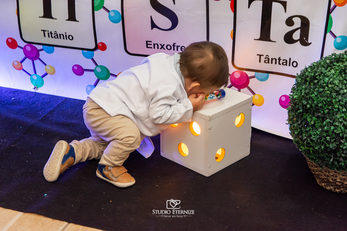 Fotografia de aniversário infantil realizado pelo Studio Eternize em Poços de Caldas. Tema da festa cientista. Aniversariante brincando com a decoração.
