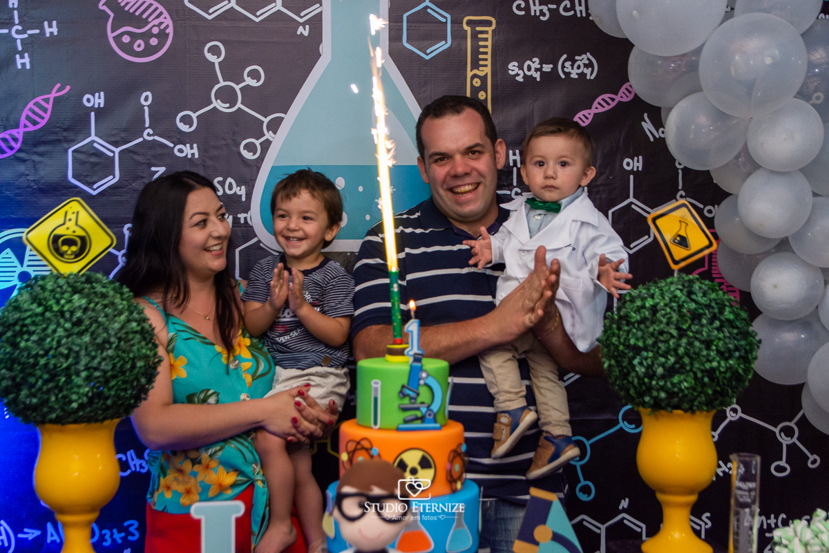 Fotografia de aniversário infantil realizado pelo Studio Eternize em Poços de Caldas. Tema da festa cientista. Aniversariante, seus pais e seu irmão cantando parabéns.