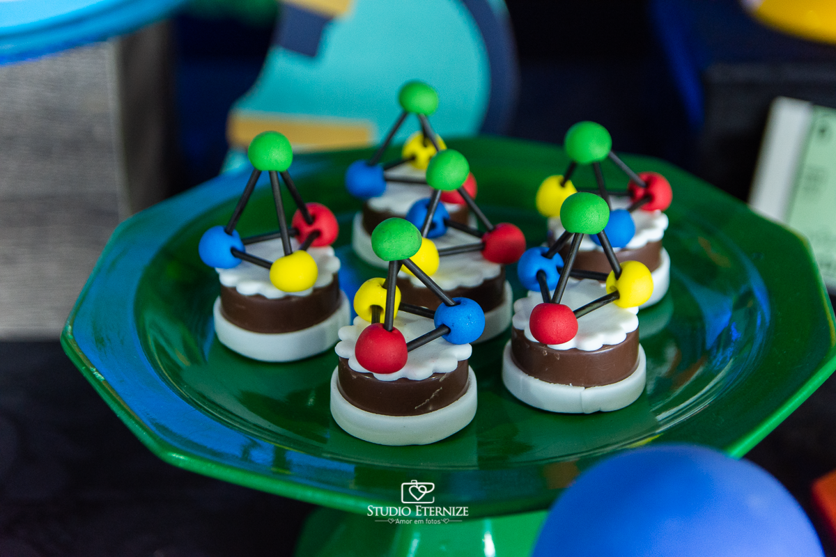 Fotografia de aniversário infantil realizado pelo Studio Eternize em Poços de Caldas. Tema da festa cientista. Detalhe de doces personalizados com elementos científicos.