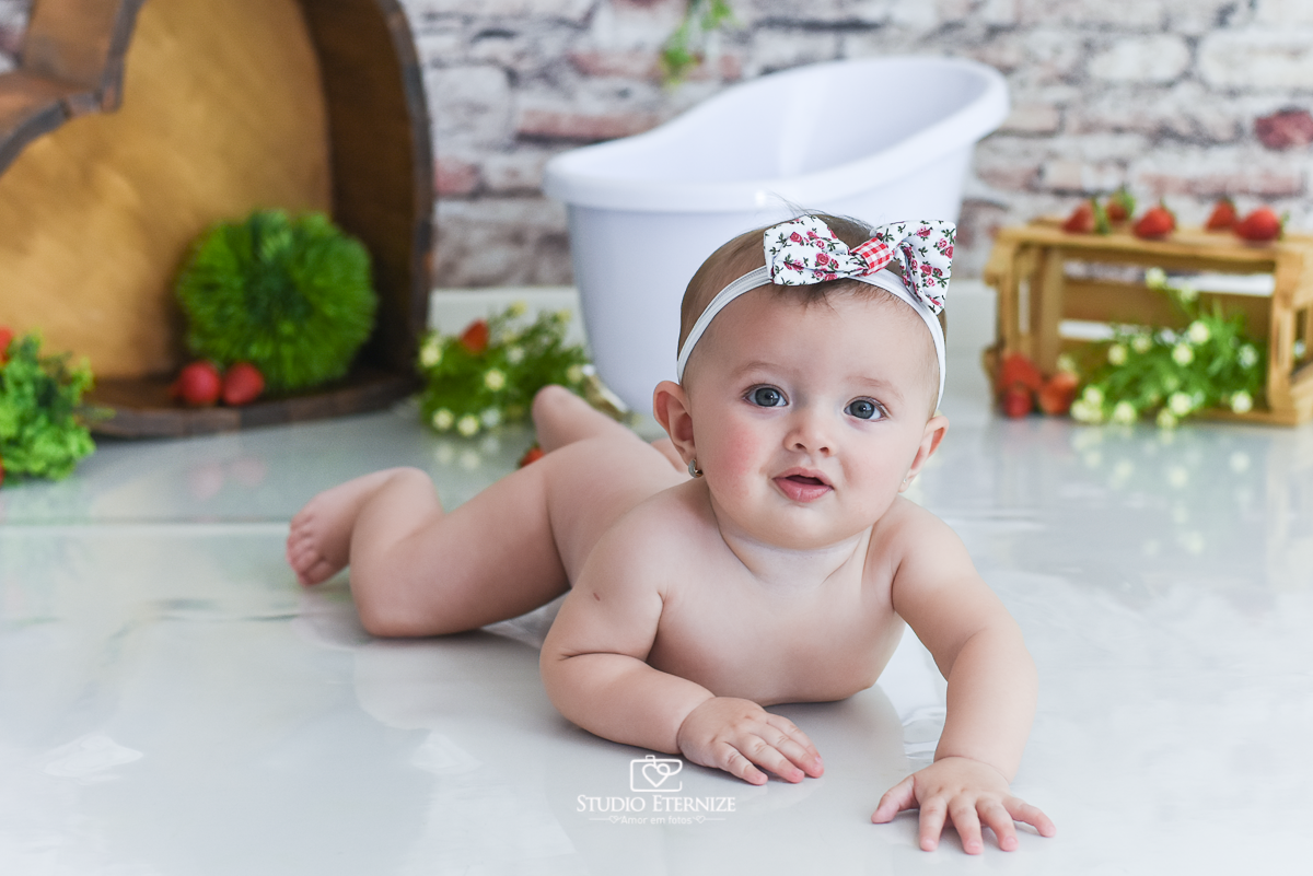 Fotografia de acompanhamento mensal do bebê realizada no Studio Eternize em Poços de Caldas - MG. Bebê menina com 6 meses de idade de bruços com o bumbum para cima, peladinha.