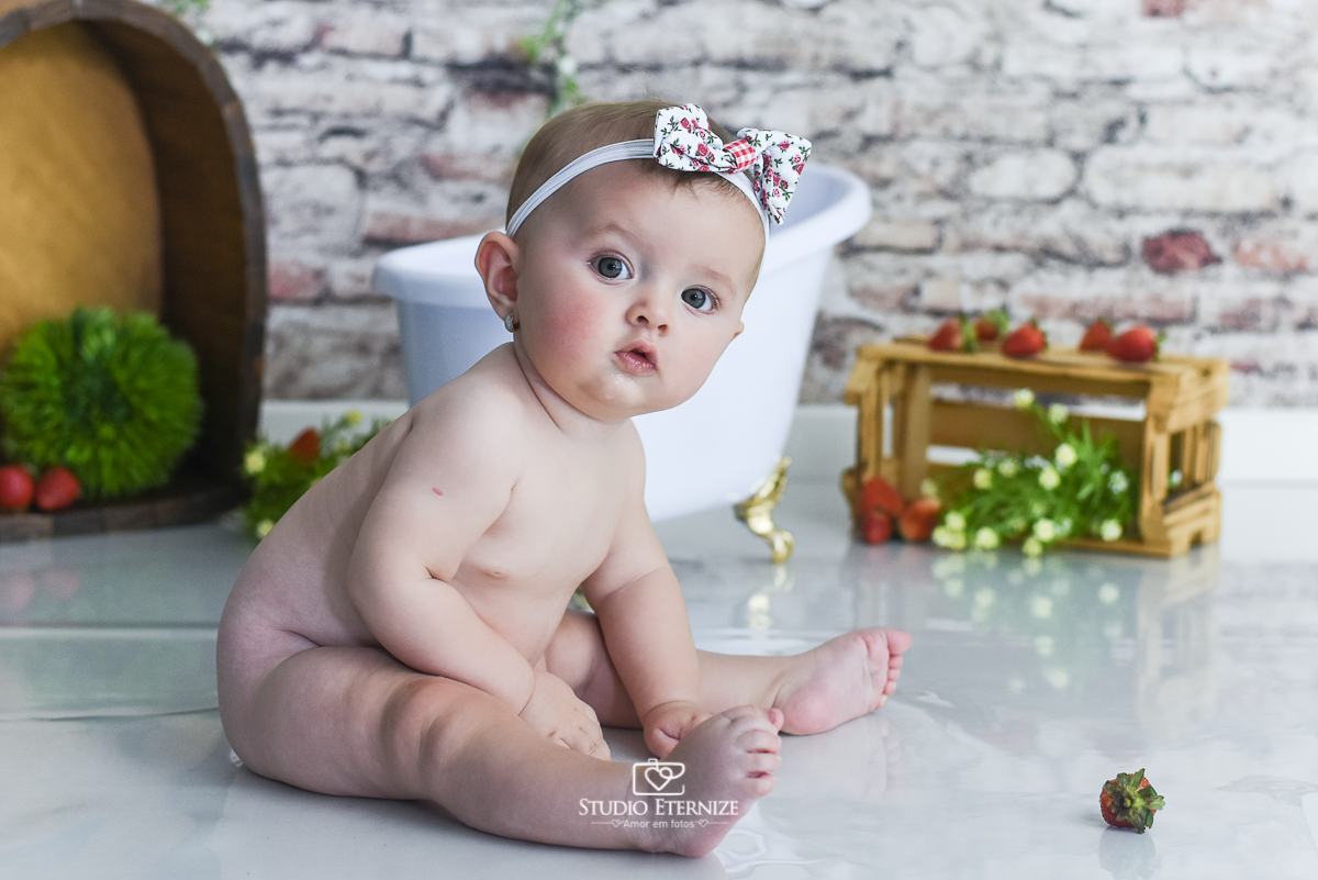 Fotografia de acompanhamento mensal do bebê realizada no Studio Eternize em Poços de Caldas - MG. Bebê menina com 6 meses de idade sentada de lado peladinha.