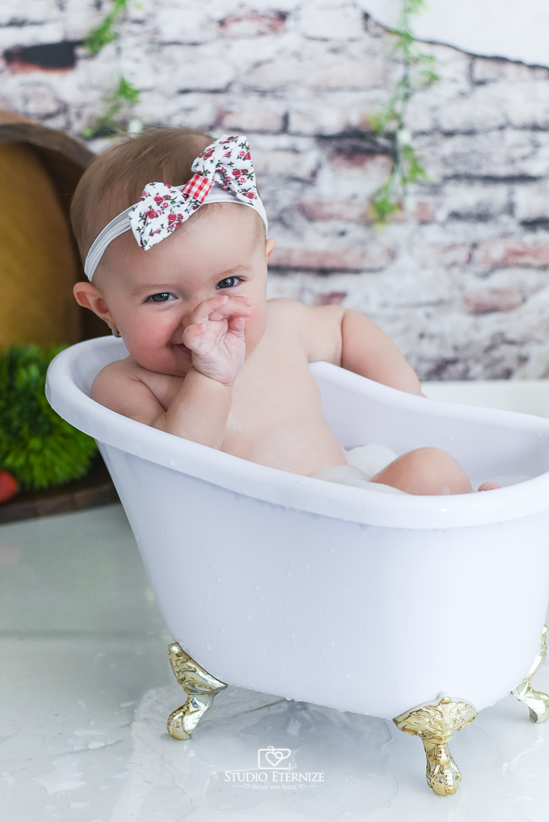 Fotografia de acompanhamento mensal do bebê realizada no Studio Eternize em Poços de Caldas - MG. Bebê menina com 6 meses de idade dentro de uma banheira branca .