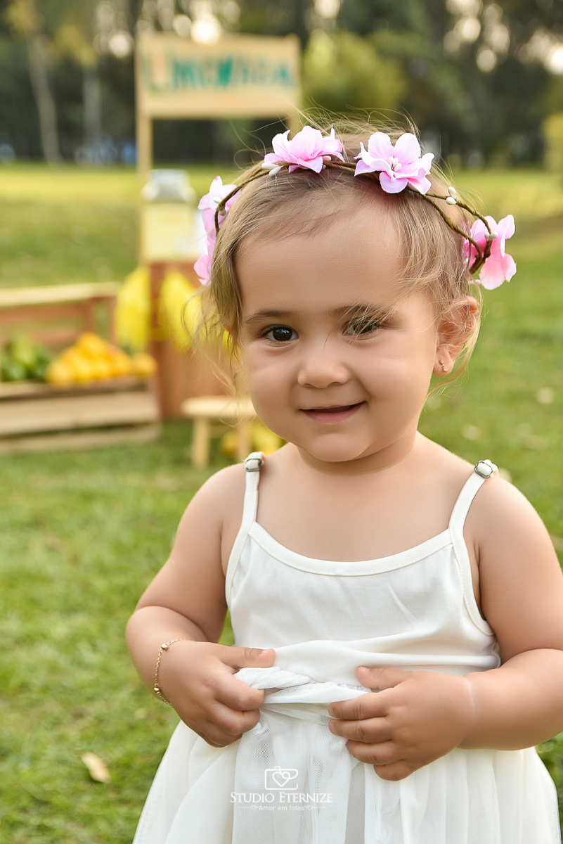 Sessão fotográfica infantil externa com cenário da barraca da limonada. Close da criança em frente da  barraca da limonada sorrindo.